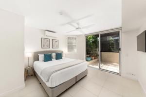 een witte slaapkamer met een bed en een raam bij Maison Noosa in Noosa Heads