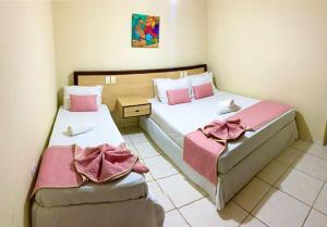 2 camas en una habitación pequeña con sábanas rosas en Pousada Mar Da Barra, en Maragogi