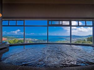 a large swimming pool with a view of the ocean at The Yuinchi Hotel Nanjo in Nanjo
