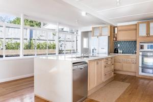 una cocina con armarios de madera y electrodomésticos blancos en Sunshine Rise Upstairs, en Raglan 21 fotos más