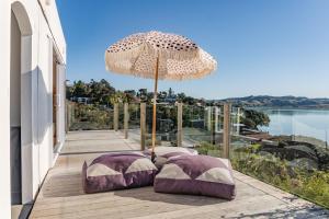 un patio con 2 almohadas y una sombrilla en Sunshine Rise Upstairs, en Raglan