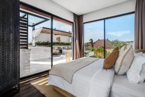ein Schlafzimmer mit einem Bett und einem großen Fenster in der Unterkunft Priviere Luxury Villa - Canggu in Canggu