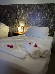 uma cama branca com toalhas e flores em Casa da Lagoa em Jijoca de Jericoacoara