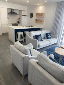 a living room with couches and a kitchen at Waterfront 209 in Paihia