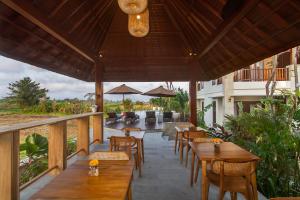 a restaurant with wooden tables and chairs on a balcony at Odessa Village by Pramana Villas in Gianyar
