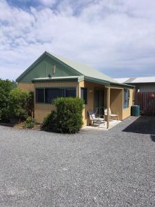 a house with a table and a chair in the driveway at Bay Cottages in Kaikoura