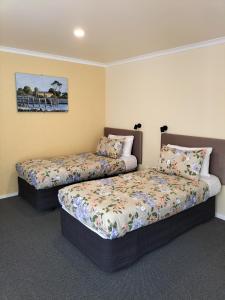 a bedroom with two beds and a painting on the wall at Bay Cottages in Kaikoura