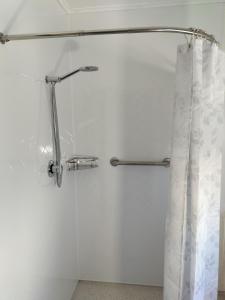 cortina de ducha en un baño blanco con barra de ducha en Bay Cottages, en Kaikoura