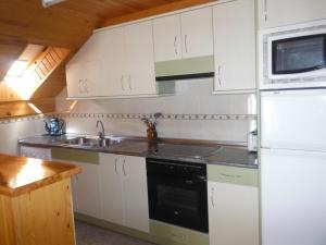 a kitchen with white cabinets and a sink and a refrigerator at Apartamentos Casa Borja in Salinas de Bielsa