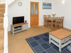 a living room with a television and a dining room table at Mulberry Cottage - Uk45432 in Isle of Whithorn