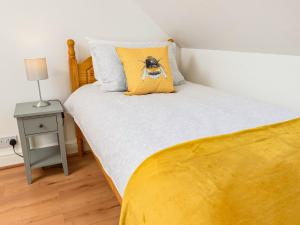 Una cama con una almohada amarilla con un perro. en Mulberry Cottage - Uk45432, en Isle of Whithorn