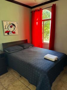 a bedroom with a bed and a window with red curtains at MonBlanc in San Salvador