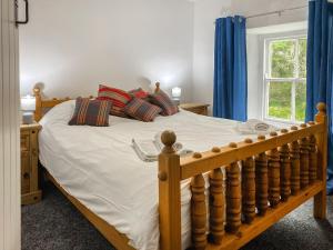 a bedroom with a wooden bed with blue curtains at The Farmhouse in Pelcomb