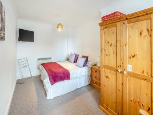 a bedroom with a bed and a wooden cabinet at Fair Isle Holiday Cottages - Hill Top Cottage in Newport