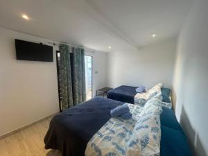 a bedroom with two beds and a flat screen tv at Sarah's Place San Andres in San Andrés