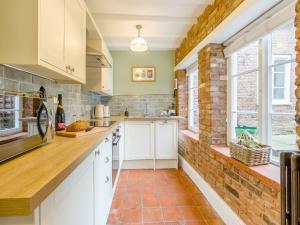 a kitchen with white cabinets and a brick wall at Abbots Retreat -uk40757 in Barrow upon Humber