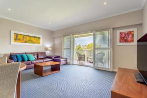 a living room with a purple couch and a balcony at Caves House Hotel Apartments in Yallingup