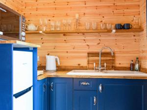 a kitchen with blue cabinets and a sink at Orchard Cabin-rowan - Uk45435 in Isle of Whithorn