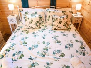 a bed with a floral bedspread and pillows on it at Orchard Cabin-rowan - Uk45435 in Isle of Whithorn
