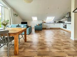 a living room with a wooden table and a kitchen at Chestnut Cottage in Wookey