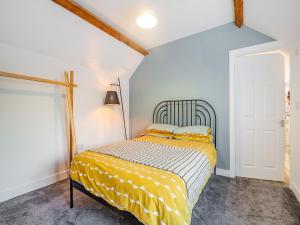 a bedroom with a bed with a yellow comforter at St Peters View in Ruthin