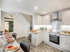 uma cozinha com armários brancos e uma mesa com comida em St Peters View em Ruthin