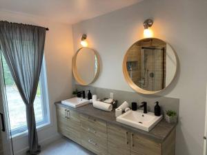 łazienka z 2 umywalkami i 2 lustrami w obiekcie Le Petit Saphir w mieście Rawdon