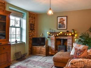 un salon avec une cheminée et une télévision dans l'établissement Kilaine Cottage, à Loftus