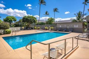 una piscina in un resort con sedie e alberi di Kihei Bay Surf 208- Updated partial oceanview studio across from beach a Kihei