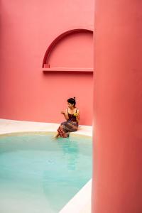 una mujer sentada en el borde de una piscina en VA Villa Jimbaran Bali, en Jimbaran