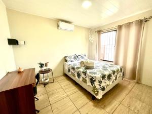 a bedroom with a bed and a window and a table at Oasis Arenal Villa Pool & Arenal Volcano View in Fortuna +9 photos