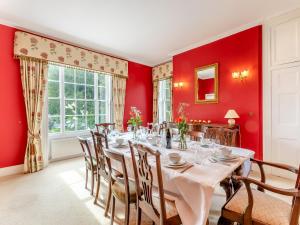 comedor con paredes rojas y mesa con sillas en Manor Farm House - Uk45276, en Sculthorpe