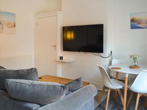 a living room with a couch and a tv on a wall at Whittles Apartment in Hornsea