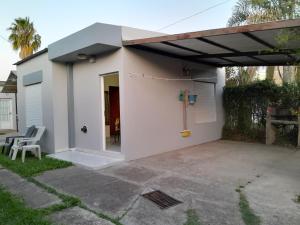 Casa blanca pequeña con toldo y patio en Bungalows Estela en Villa Elisa
