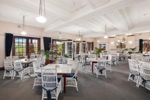 a dining room with white tables and chairs at Caves House Hotel Apartments in Yallingup