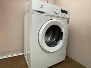 eine weiße Waschmaschine in einer Ecke eines Zimmers in der Unterkunft Beautiful 3BR Home - 8 min from Centre by Sakura 