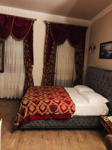 um quarto com uma cama com um cobertor vermelho e cortinas em BeyPort Hotel Taksim em Istambul