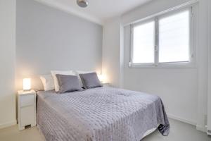 ein weißes Schlafzimmer mit einem Bett und einem Fenster in der Unterkunft Beautiful and cosy flat with terrace 1BR4p - Cannes in Cannes