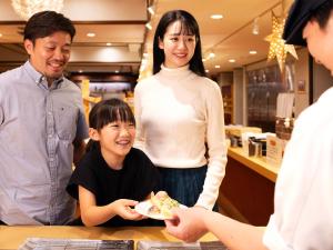 un grupo de personas de pie alrededor de una mesa comiendo comida en Hotel Ichinose, en Yamanouchi