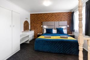a bedroom with a large bed with blue and yellow sheets at Leichhardt Motor Inn in Toowoomba