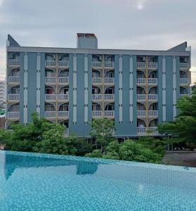a hotel with a swimming pool in front of a building at Burapha Bangsaen Garden Apartment in Bangsaen