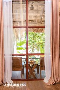 een kamer met een groot raam met een tafel en stoelen bij La Maison De Buoc in Mai Chau