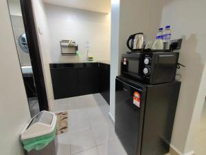 una pequeña cocina con nevera negra y encimera en Alish Studio Apartment with Pool, Netflix, Wifi, en Gua Musang