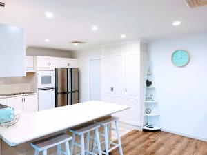 una cucina con armadi bianchi e piano di lavoro bianco di 100m to Beach&Shop Spacious Pristine One Story Family Home a Batemans Bay