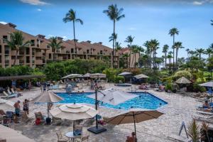 einen Pool in einem Resort mit Leuten, die um ihn herum sitzen in der Unterkunft Kamaole Sands 2-306- Kamaole Sands spacious, updated, and Oceanview! in Wailea