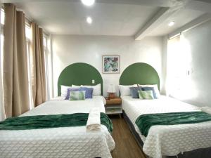 two beds in a room with green and white at Hotel Casa Tenango in Cobán
