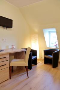 ein Wohnzimmer mit einem Schreibtisch und 2 Stühlen in der Unterkunft Gasthof und Hotel Roter Hirsch in Claußnitz