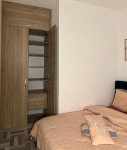 1 dormitorio con 1 cama y armario de madera en SYN - Corniche en Brazzaville