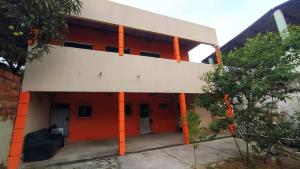 czerwono-biały budynek z pomarańczowymi kolumnami w obiekcie Casa de temporada em Cabuçu w mieście Saubara