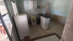 a small kitchen with a refrigerator and a sink at Casa de temporada em Cabuçu in Saubara